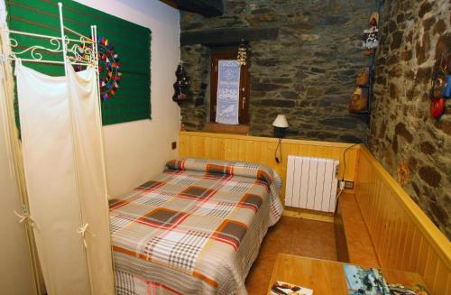 a bedroom with a bed and a stone wall at Casa de Abril 1 in San Cristóbal de Valdueza