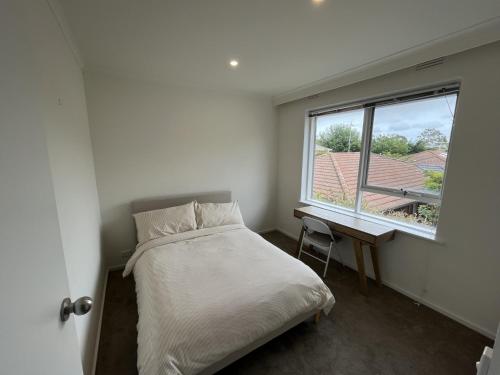 a bedroom with a bed and a desk and a window at Private Cozy Room in a Spacious Flat in Carnegie in Carnegie