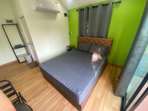 a bed in a room with a green wall at รักกันต์ รีสอร์ท in Ban Sakat Namman