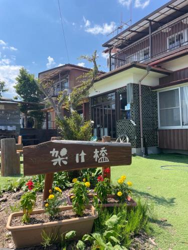 a sign in a garden in front of a house at Guesthouse Kakehashi in Kesennuma