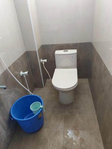 a bathroom with a toilet and a blue bucket at Rajeshwari Tower & Residency in Tiruvannāmalai