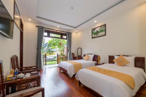 een hotelkamer met twee bedden en een raam bij Paradise Boutique Hoi An in Hội An