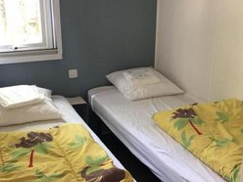 zwei Einzelbetten in einem Zimmer mit Fenster in der Unterkunft Mobil-home confortable avec terrasse à Saint-Gérons - API-1-52-1315 in Saint-Étienne-Cantalès