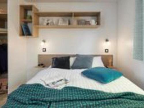 ein Schlafzimmer mit einem großen Bett und blauen Kissen in der Unterkunft Mobil-home 35m² avec Terrasse - Saint-Gérons - API-1-52-1314 in Saint-Étienne-Cantalès