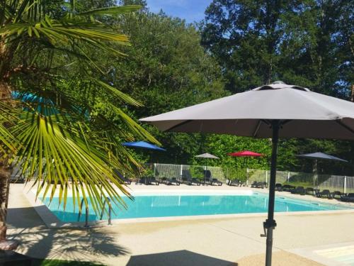ein weißer Regenschirm neben einem Pool in der Unterkunft Mobil-home 27m² à Saint-Gérons avec terrasse - API-1-52-1316 in Saint-Étienne-Cantalès