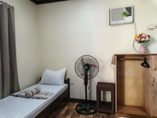a room with a bed with a fan and a table at Nay Nilda Tourist Inn in Itaytay