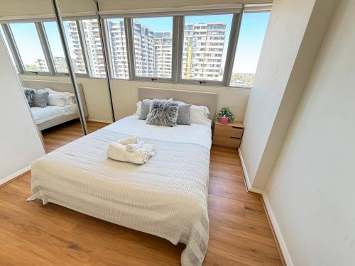 a bedroom with a large bed in a room with windows at Burwood Luxe Urban Escape in Sydney