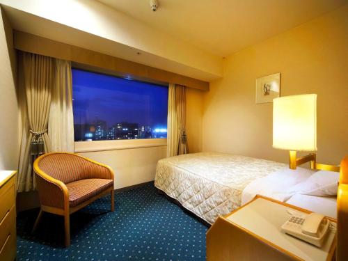una stanza d'albergo con un letto e una finestra di Hotel Crown Palais Hamamatsu a Hamamatsu