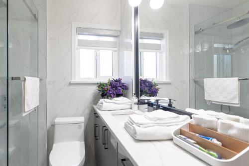 a white bathroom with a sink and a mirror at Vancouver Cozy Cove in Vancouver