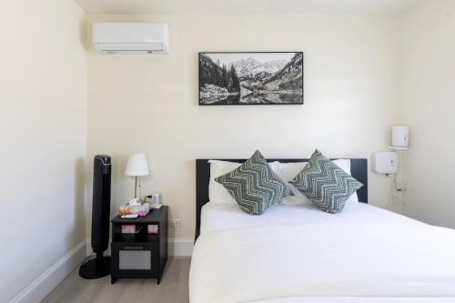a bedroom with a white bed with pillows and a night stand at Vancouver Cozy Cove in Vancouver