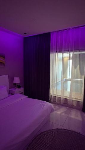 een paarse kamer met een bed en een raam bij شاليهات لورين الفندقية in Taif