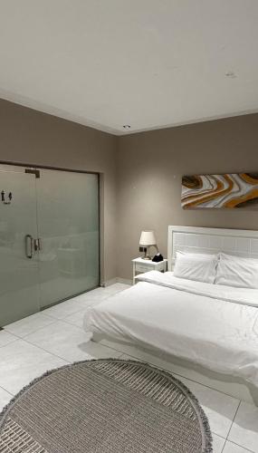 een slaapkamer met een groot wit bed en een glazen deur bij شاليهات لورين الفندقية in Taif