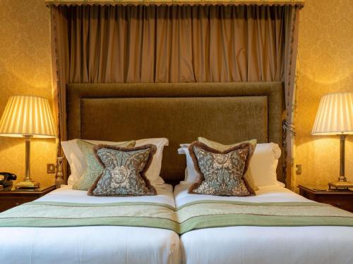 a bedroom with a large bed with two pillows at Lucknam Park, Emblems Collection in Chippenham