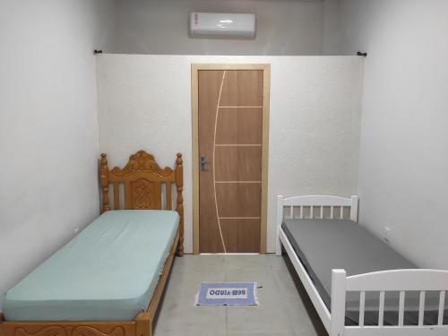 a room with two beds and a door with a sign on the floor at Apartamento Nami 2 in Cacoal
