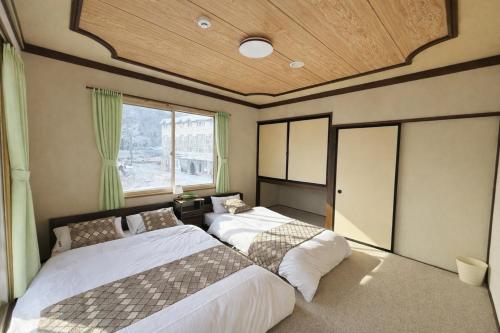 a bedroom with two beds and a large window at 雪场缆车站旁-START HOUSE PIAA-Ski IN Ski OUT in Minami Uonuma