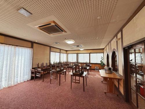 a large room with tables and chairs and windows at 雪场缆车站旁-START HOUSE PIAA-Ski IN Ski OUT in Minami Uonuma