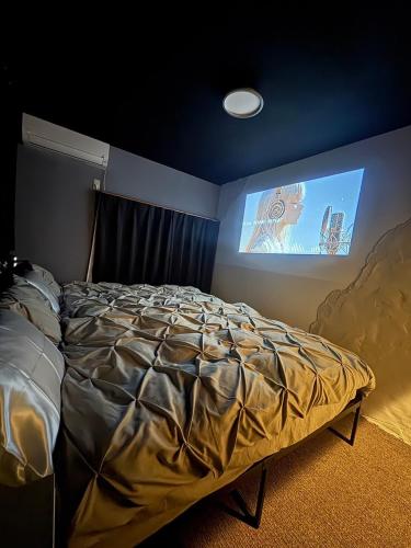 a bedroom with a bed and a tv on the wall at 最大10名 源泉掛け流し露天風呂付き一棟貸しNagasima Private Villa in Genroku