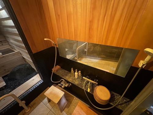 a bathroom with a tub with a toilet and a sink at 最大10名 源泉掛け流し露天風呂付き一棟貸しNagasima Private Villa in Genroku
