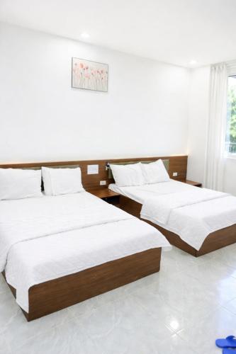 two beds in a room with white walls at 72M Hotel Visip in Vinh