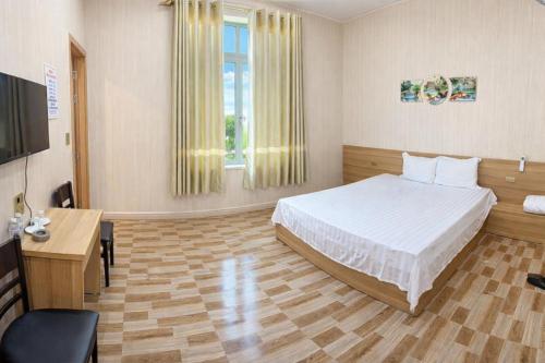 een slaapkamer met een bed, een bureau en een televisie bij Hưng Phát Hotel - Gần Bến Xe Hà Tĩnh in Ha Tinh
