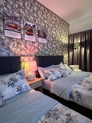 a bedroom with two beds and a table with a lamp at AbahHomeStudio Tunjung in Kota Bharu