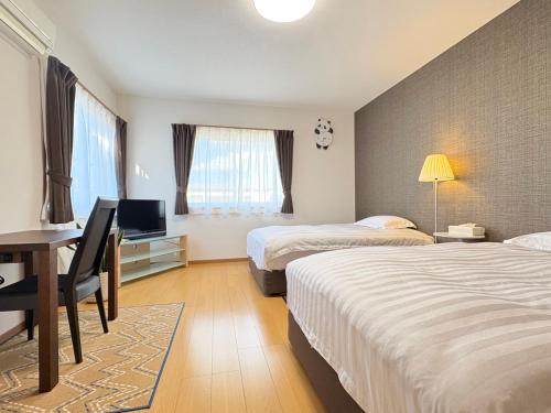 a hotel room with two beds and a desk with a computer at 松江の里東津田店 in Matsue
