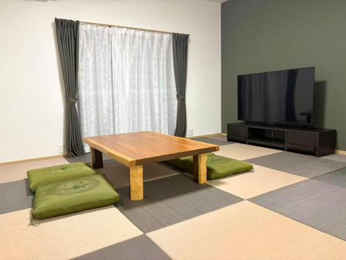 a living room with a table and a flat screen tv at 松江の里東津田店 in Matsue
