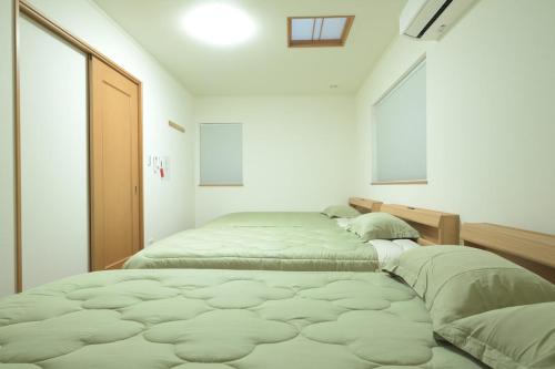 two beds in a white room with a window at Peace and Harmony House Rongsheng in Nagoya