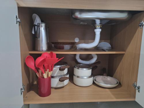 een keukenkast met servies en keukengerei bij Studio Litorâneo para Relaxar in Governador Celso Ramos