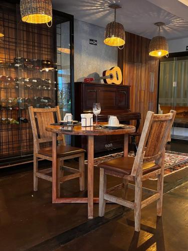 a wooden table with two chairs and a wine glass at Pousada Boutique Village della Nonna in Campos do Jordão