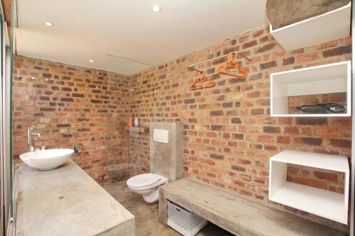 a brick walled bathroom with a toilet and a sink at Motel Mi Pi Chi in Johannesburg