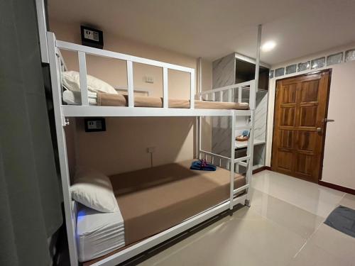 a small room with bunk beds with a door at Sabai House in Phi Phi Islands