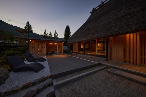 a house with a patio with two chairs and a building at えにし美山 霞月 -kagetsu- in Nantan city