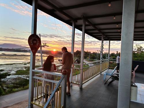 een man en een vrouw die op een balkon staan met de zonsondergang bij ชมวิว บึงโขหลง in Ban Don Klang