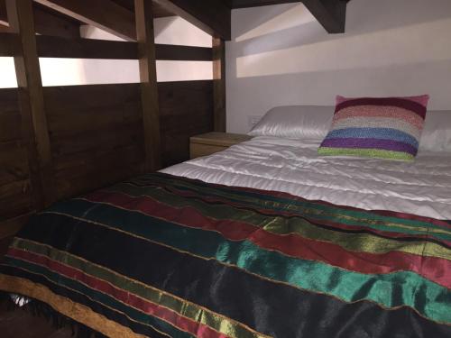 Una cama con una manta de colores encima. en Casa del Fraile en Villarrobledo