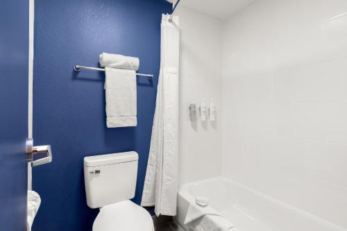 a blue bathroom with a toilet and a shower at Spark By Hilton Muskogee in Muskogee