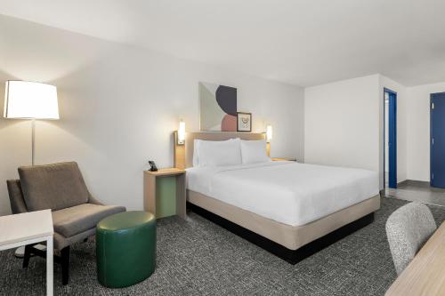 a hotel room with a bed and a chair at Spark By Hilton Muskogee in Muskogee