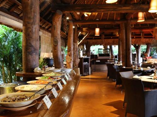 a buffet line with plates of food in a restaurant at Novotel Lombok Resort & Villas in Kuta Lombok