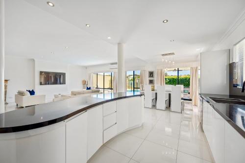 a kitchen with white cabinets and a living room at Luxury Villa W Pool & Spa 5 BEDROOMS in Coogee