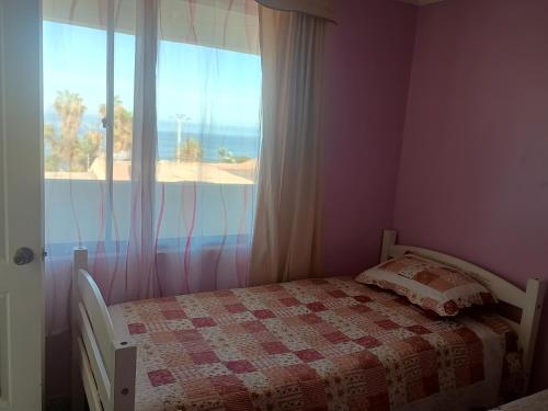 una camera da letto con un letto e una finestra con vista sulla spiaggia di Nuestro rincón a Iquique