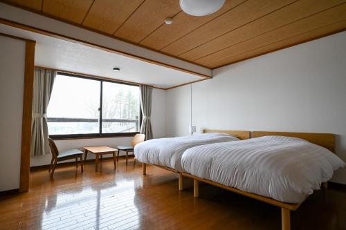 ein Schlafzimmer mit Bett, Schreibtisch und Fenster in der Unterkunft Hotel Goryukan in Hakuba