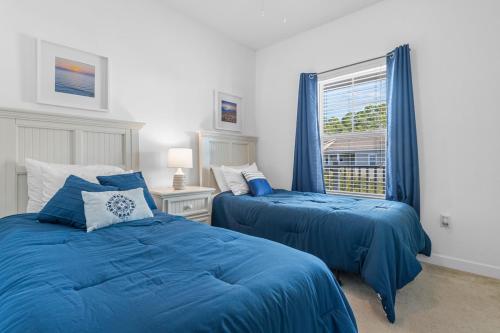 een slaapkamer met twee blauwe bedden en een raam bij Stylish Barefoot Golf Condo with Pool Access in North Myrtle Beach