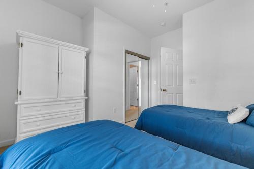 een slaapkamer met 2 blauwe bedden en een dressoir bij Stylish Barefoot Golf Condo with Pool Access in North Myrtle Beach
