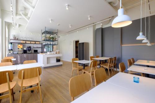 a dining room with tables and chairs and a kitchen at Zleep Hotel Prindsen Roskilde in Roskilde