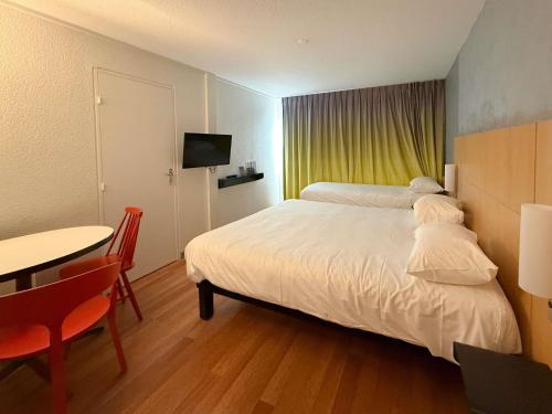 ein Schlafzimmer mit einem weißen Bett und einem Tisch und einem Tableablish in der Unterkunft ibis Rennes Beaulieu in Cesson-Sévigné