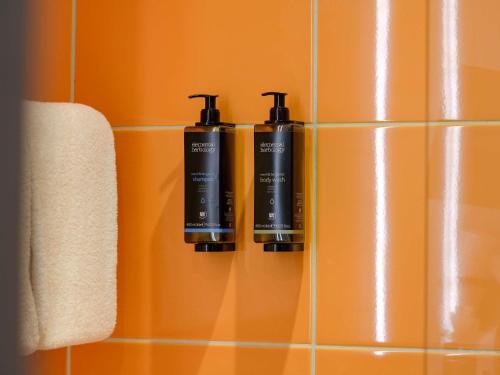 dois frascos de odorizadores estão pendurados na parede do banheiro em Mercure Hotel Köln West em Colónia