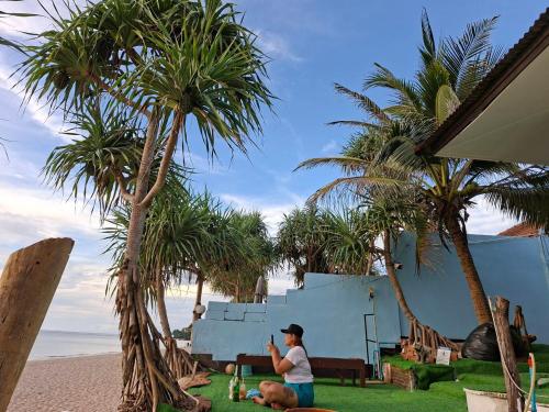Eine Frau sitzt am Strand unter Palmen in der Unterkunft Horizon Bungalow Koh-Lanta in Ko Lanta