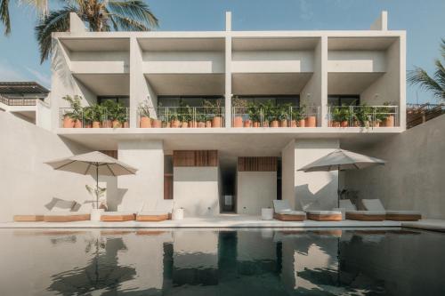 a villa with a swimming pool with chairs and umbrellas at Notto Zicatela Hotel in Puerto Escondido
