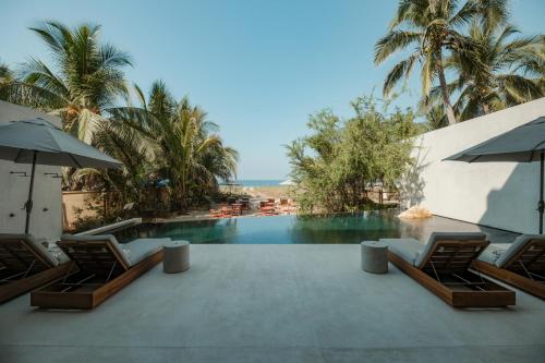 een zwembad met stoelen en parasols naast een resort bij Notto Zicatela Hotel in Brisas de Zicatela