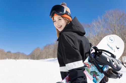 una ragazza che tiene uno snowboard nella neve di Hotel SIMIZU a Tokamachi
